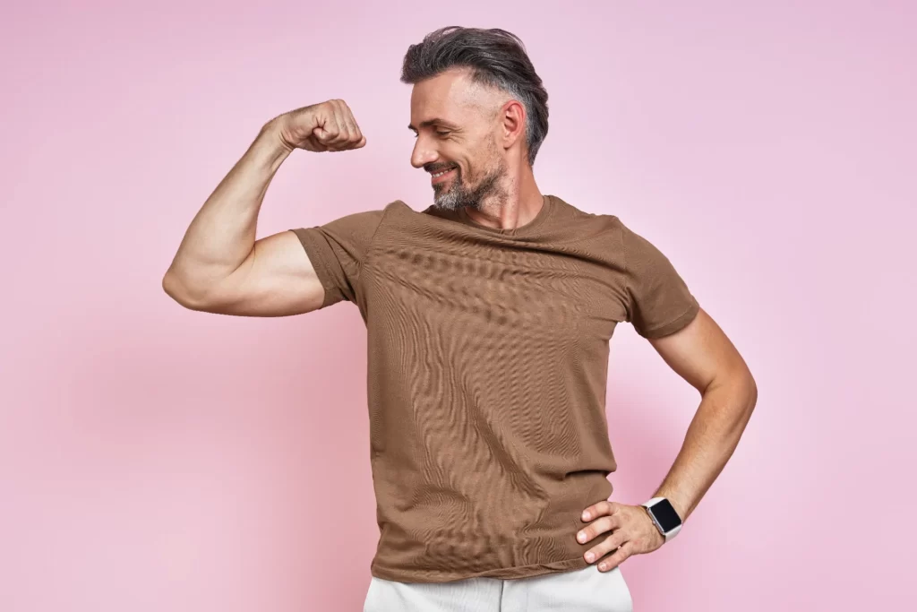 smiling man flexing his arm in studio utc