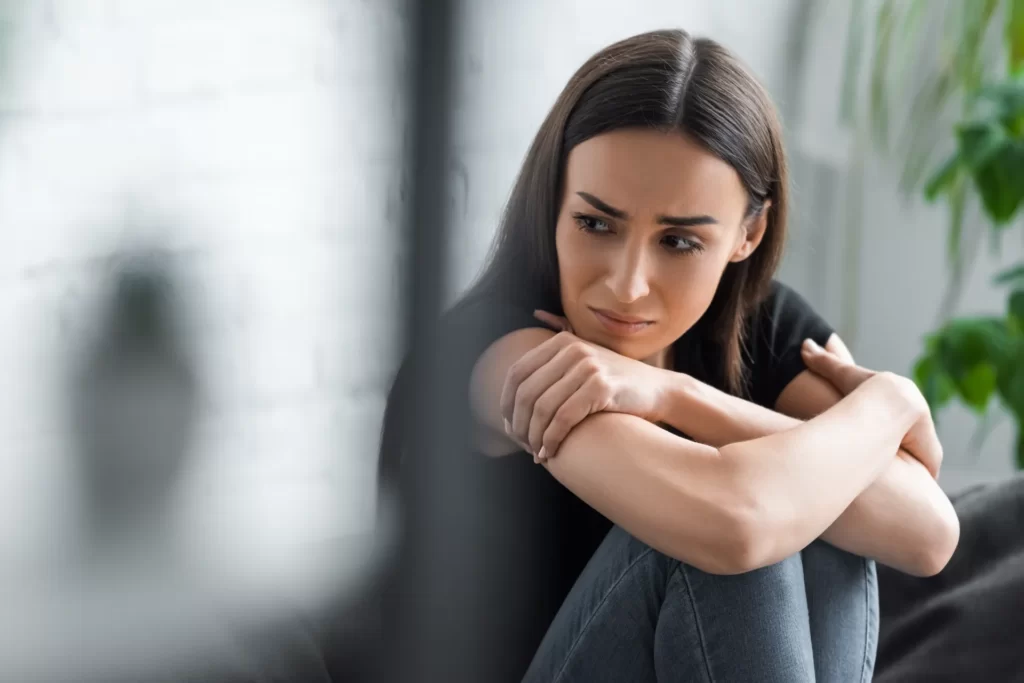 sad woman sitting on sofa in daylight utc
